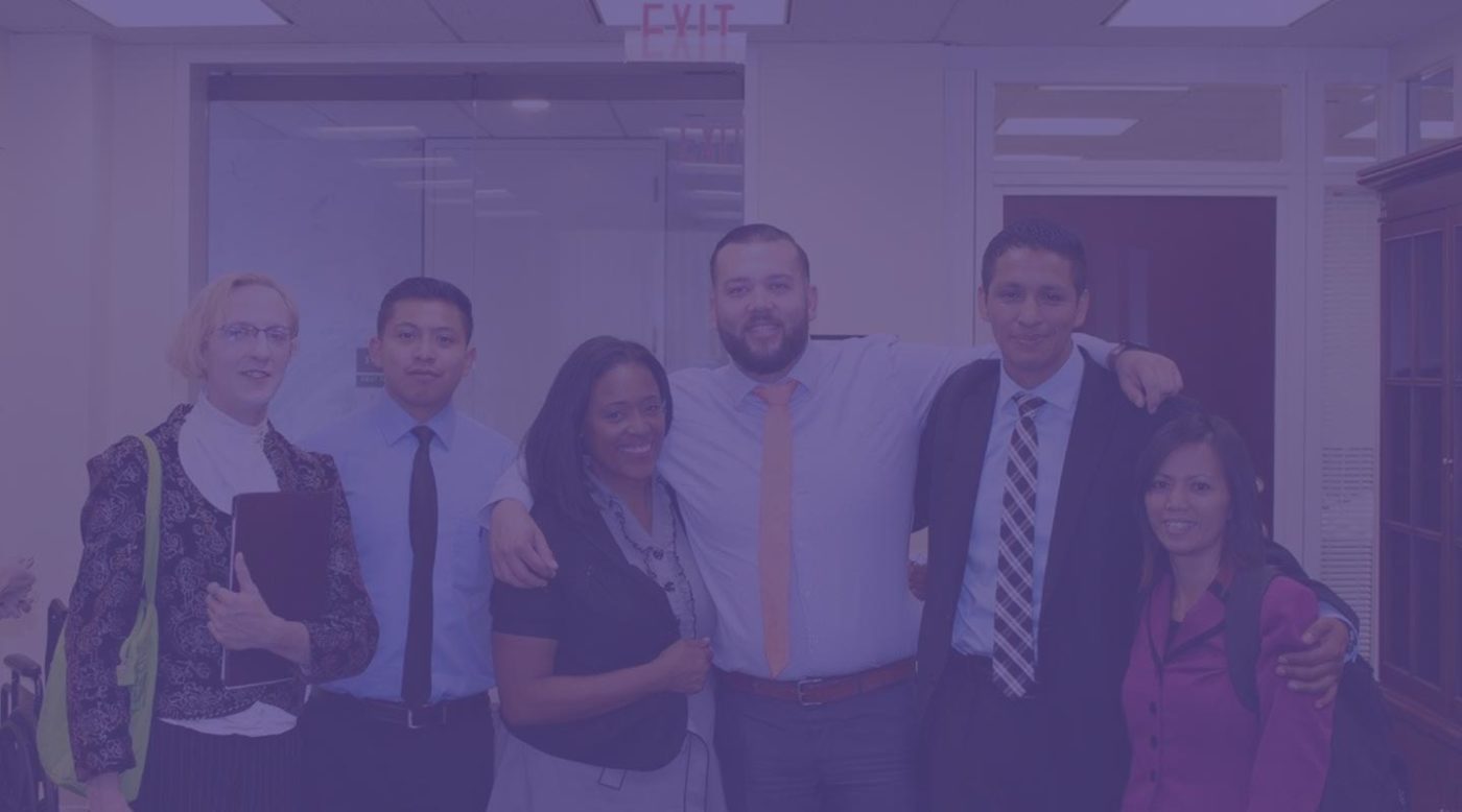 NSN Image has a purple filter over it but shows a group of well-dressed and smiling survivors standing together and smiling. They are doing work on behalf of the NSN.